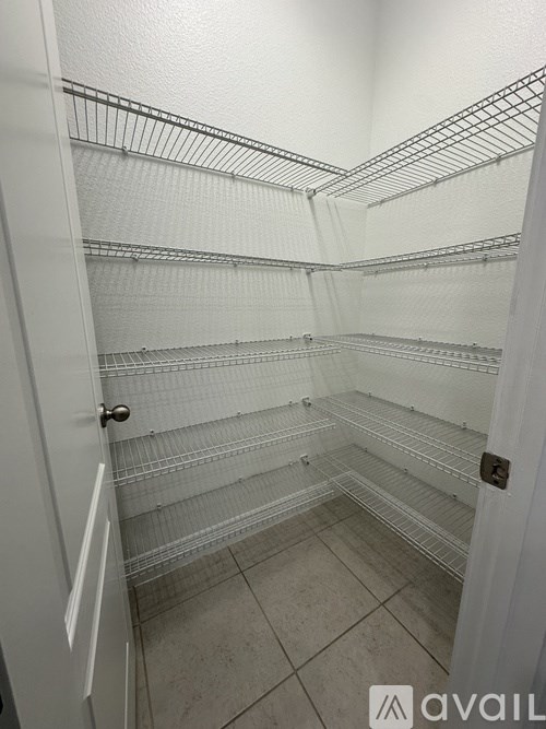 Empty walk-in closet with white shelves and a white door.