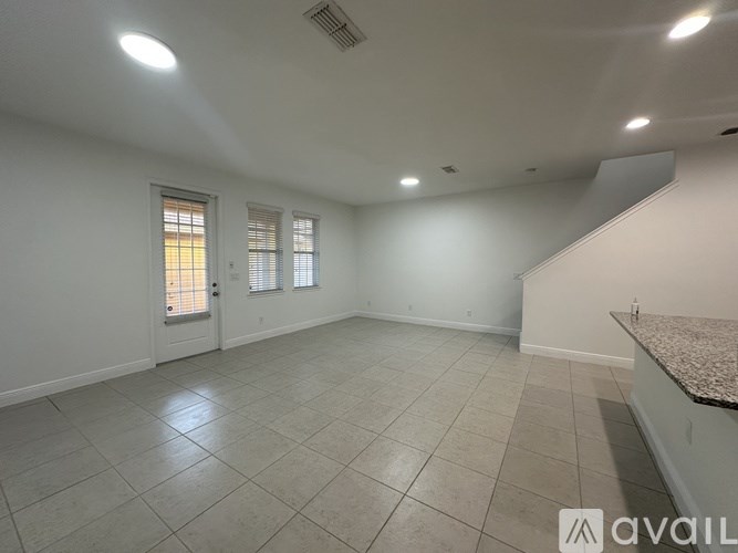 A spacious room with tiled flooring and a window with blinds.