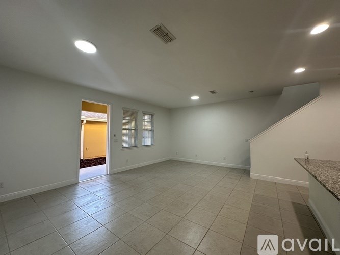 A spacious room with tiled flooring and a staircase on the right side.