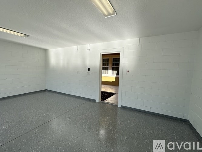 A room with white walls and a door leading to another room.
