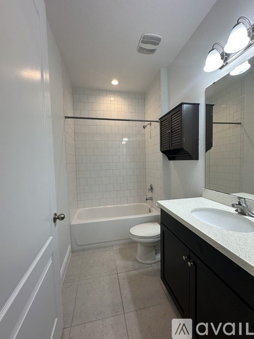 A bathroom with a white tub, sink, and toilet.