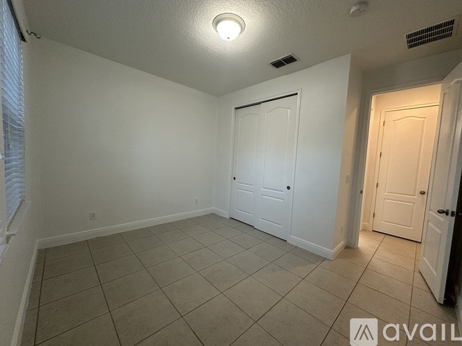 A room with a white door and a window with blinds.