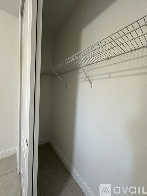 Empty white closet with a wire shelf.