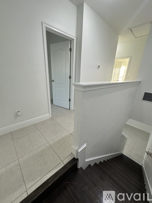 A white door is in a white room with a wooden floor.