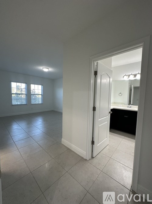 A room with a white door and a window with a view of a fence and trees.