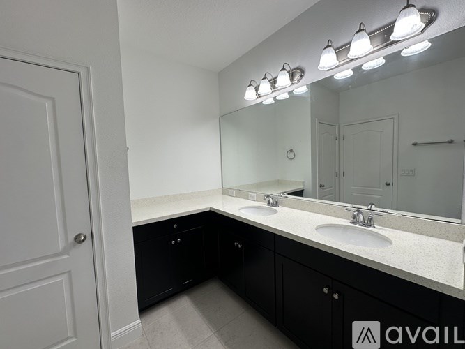 A bathroom with a sink, mirror, and lighting fixtures.
