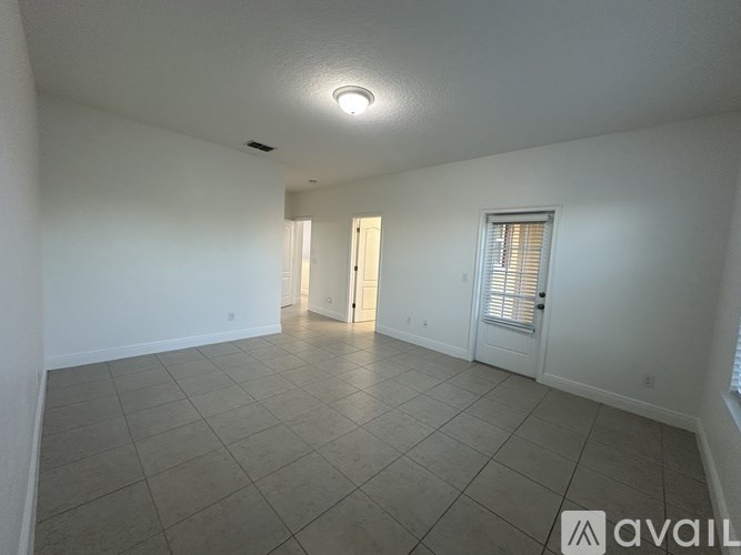 A spacious room with tiled flooring and a doorway leading to another room.
