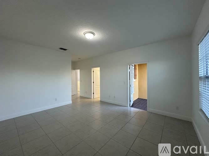 A spacious room with tiled flooring and a single light fixture on the ceiling.