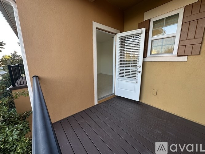 A balcony with a white door and a window with white blinds.