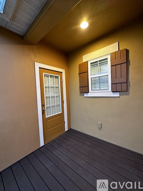 A room with a brown door and a window with brown shutters.