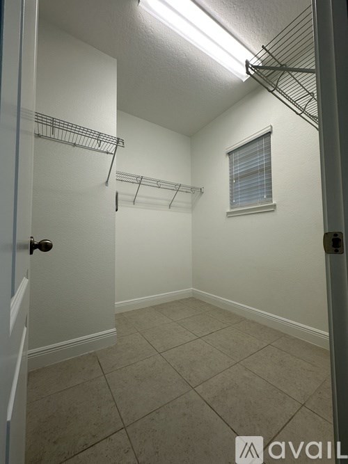A small, empty room with a door on the left and a window on the right.