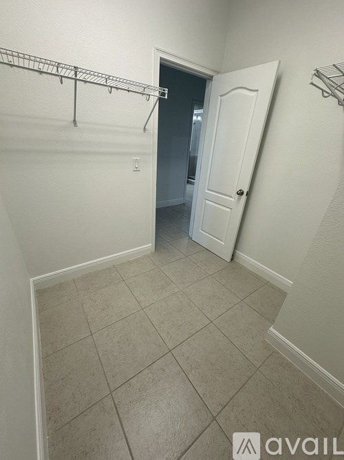 A white hallway with a door and a shelf on the wall.