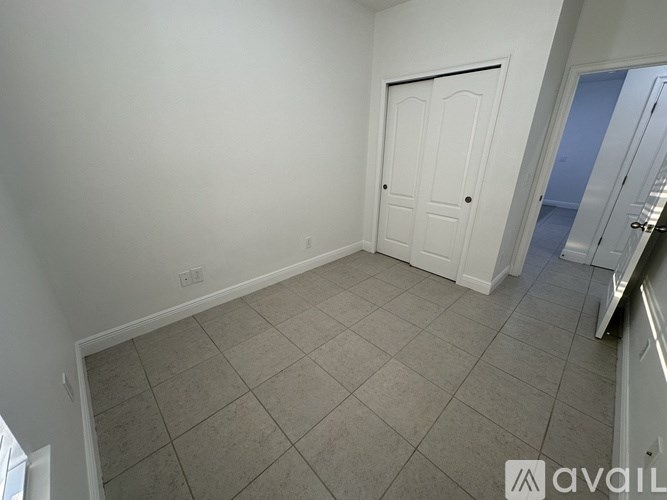 A room with a white door and tiled floor.