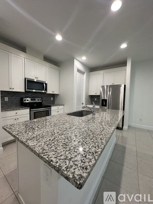 A kitchen with granite countertops and white cabinets.