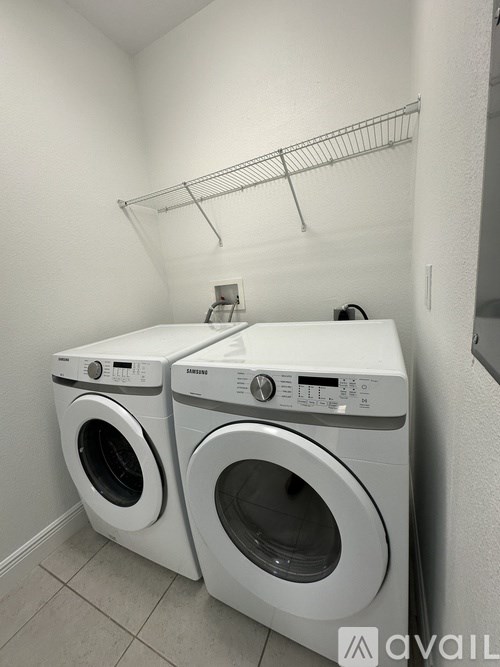 Two white front loading washing machines in a laundry room.