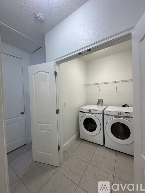 A laundry room with two washing machines and a door open.