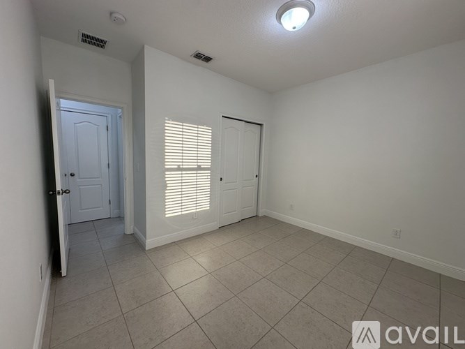 A room with a door and a window with blinds.
