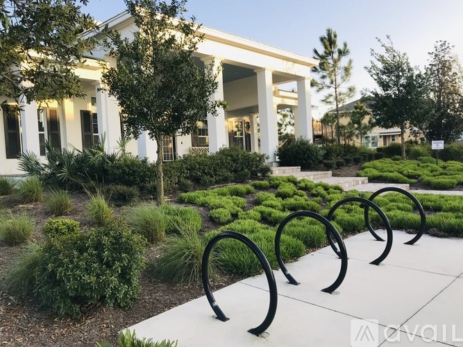 A white building with columns and a row of bushes in front.