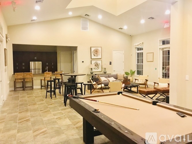 A billiard table is in the middle of a room with a bar and seating area.