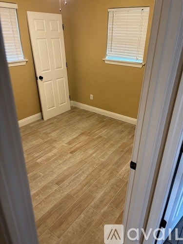 A room with a white door and a window with blinds.