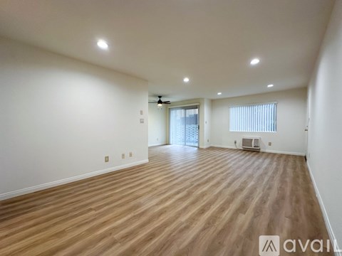 A spacious room with wooden flooring and white walls.