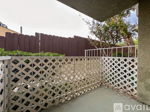 A white lattice fence with a brown fence in the background.