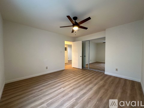 A room with a ceiling fan and wooden flooring.