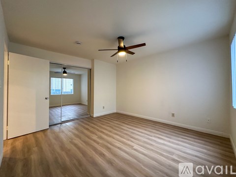 A spacious room with a ceiling fan and wooden flooring.