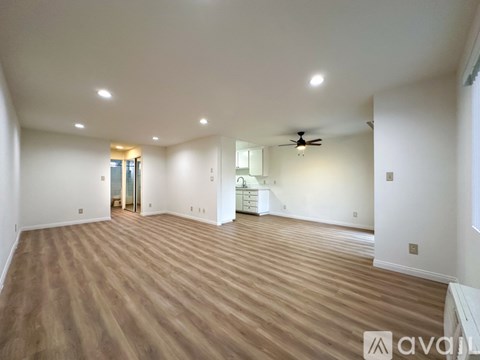 A spacious room with wooden flooring and a ceiling fan.