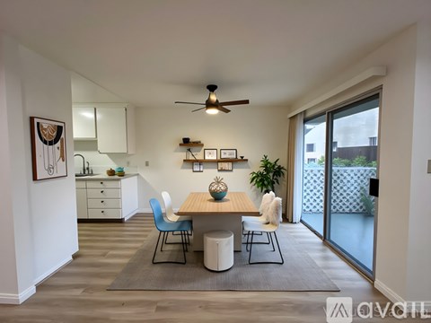 A modern dining room with a table, chairs, and a ceiling fan.
