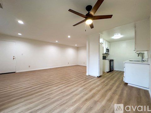 A room with a ceiling fan and wooden flooring.