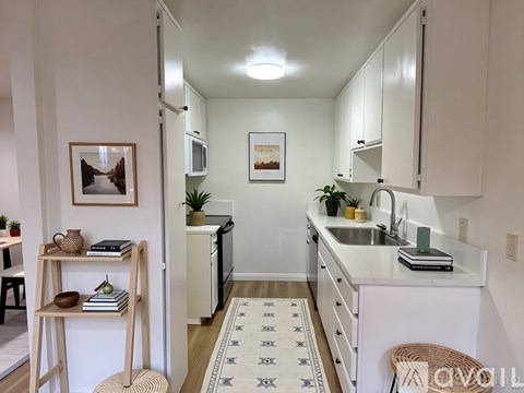 A kitchen with white cabinets and a rug on the floor.