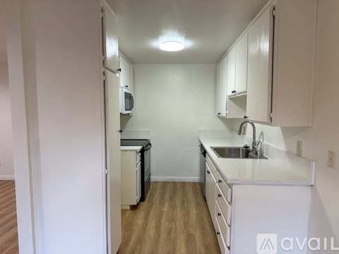 A kitchen with white cabinets and a wooden floor.
