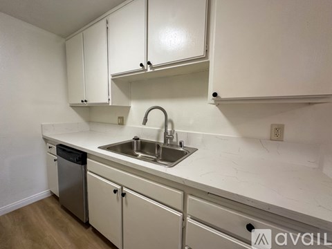A kitchen with white cabinets and a marble countertop.