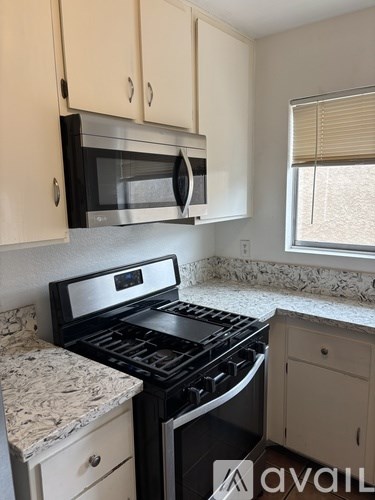 A kitchen with a black stove top oven and a microwave above it.