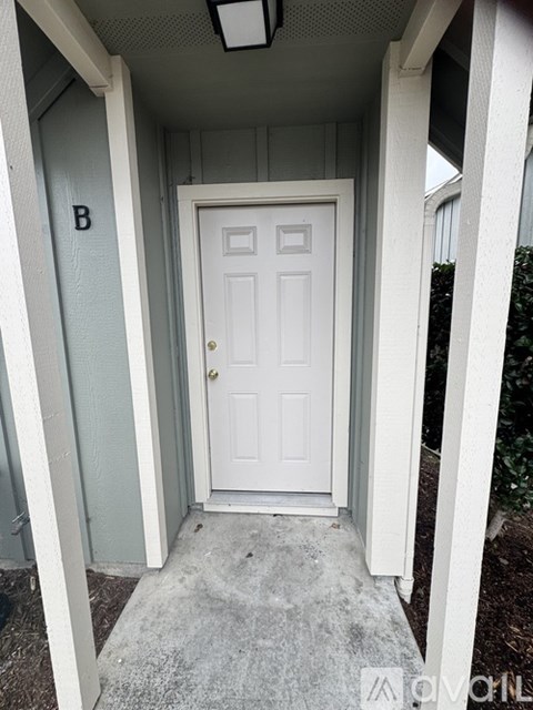 A white door is in a white frame with a letter B on the wall.