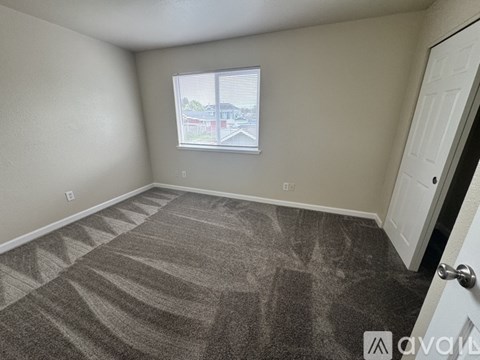 A room with a carpeted floor and a window with blinds.