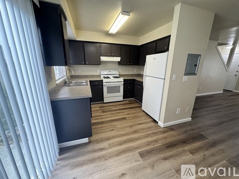 A kitchen with black cabinets and a white fridge.