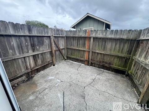 A backyard with a wooden fence and a concrete patio.