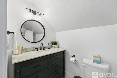 A bathroom with a marble countertop and a round mirror above it.