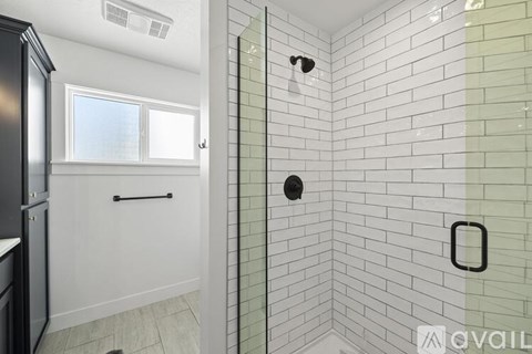 A bathroom with a glass shower door and a window.