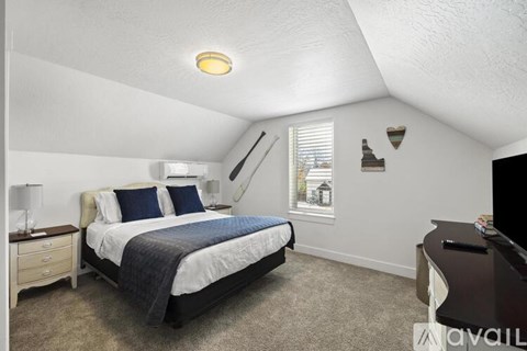 A bedroom with a bed, nightstand, and window.