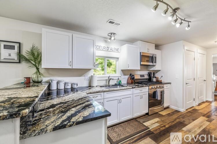 A kitchen with marble countertops and white cabinets.