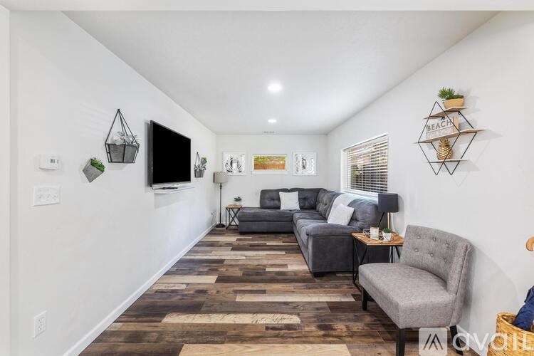 A living room with a grey couch and a wooden floor.