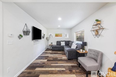 A living room with a grey couch and a wooden floor.