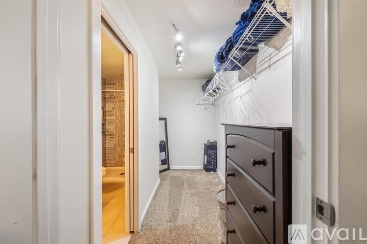 A hallway with a carpeted floor, a black dresser, and a white wall.