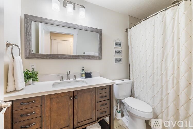 A bathroom with a white sink, toilet, and a mirror above a vanity.