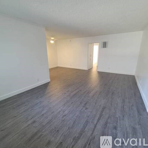 A spacious room with wooden flooring and white walls.