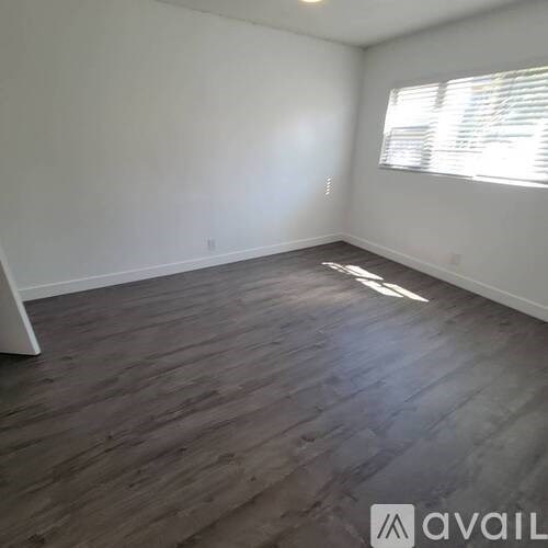 A room with wooden flooring and a window with blinds.