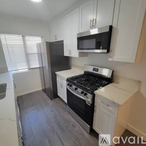 A kitchen with black appliances and white cabinets.